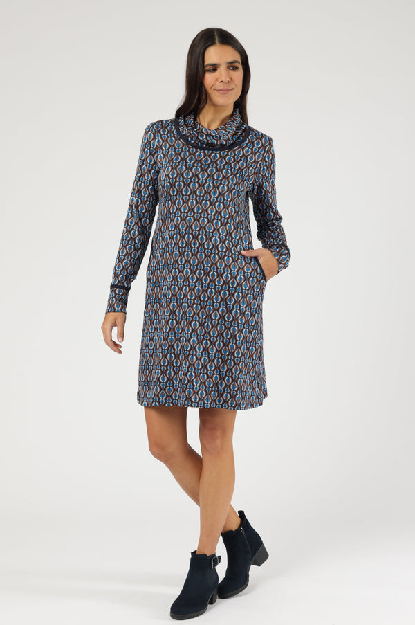 Knieumspielendes Langarm-Kleid mit geometrischem Muster in hellblau, Braun und Petrol. Besondere Details sind der weite, umschlagbare Kragen sowie die dunkelbraun paspelierten Eingrifftaschen und Ärmelbündchen.