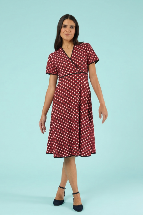 Elegantes rotes Wickelkleid mit weißem Punktemuster, V-Ausschnitt und schwarzen Kontrastpaspeln vor hellblauem Hintergrund – Damen Sommerkleid mit kurzen Ärmeln.