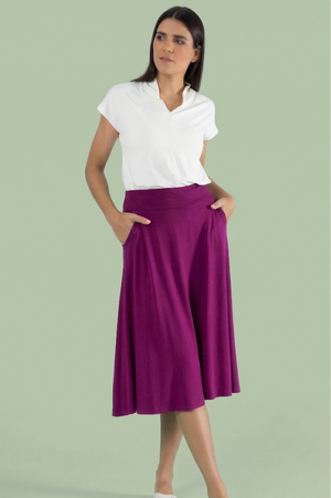 Damen Rock Lou Soft Berry in intensivem Beere-Lila – schwingender Midirock mit seitlichen Taschen vor Salbeigrünem Hintergrund